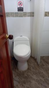a white toilet in a bathroom with a sign on the wall at Apartamentos Freddy's Tours in Santa Marta