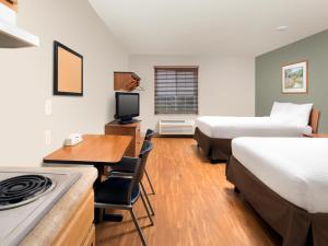 um quarto de hotel com duas camas e uma secretária e uma cozinha em Extended Stay America Select Suites - Wichita - Airport em Wichita