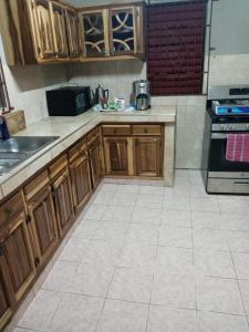 a kitchen with wooden cabinets and a tile floor at Inviting 2-Bed House in Fair Prospect in Port Antonio