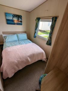 a small bedroom with a bed and a window at The Jones's Family Caravan with private decking - Presthaven in Prestatyn