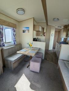 uma pequena sala de estar com uma mesa e um sofá em The Jones's Family Caravan with private decking - Presthaven em Prestatyn