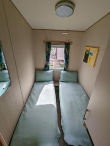 a small room with two beds in it with a window at The Jones's Family Caravan with private decking - Presthaven in Prestatyn