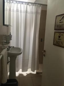 a bathroom with a white shower curtain and a sink at Departamento PRINGLES - con cochera in La Rioja