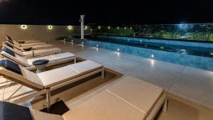a swimming pool with lounge chairs on a roof at night at Venit Barra Hotel in Rio de Janeiro