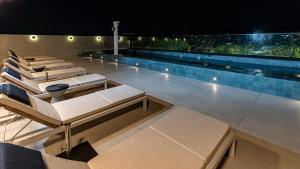 einen Swimmingpool mit Liegestühlen auf dem Dach in der Nacht in der Unterkunft Venit Barra Hotel in Rio de Janeiro