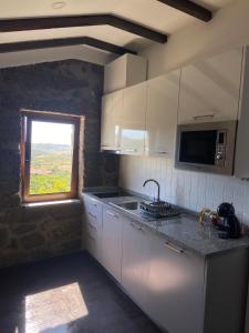 a kitchen with white cabinets and a window and a sink at Quinta da Cortelhinha Turismo Rural in Oliveira do Hospital