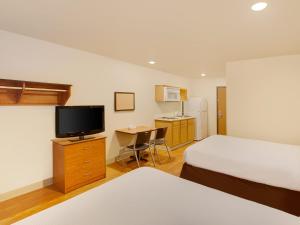 a hotel room with two beds and a television at Extended Stay America Select Suites - Shreveport - Airport in Shreveport
