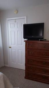 a bedroom with a television on a dresser with a door at 2 Bedroom Condo in Rehoboth Beach w/ New Bed in Rehoboth Beach