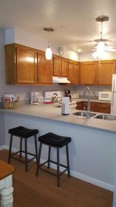 a kitchen with two stools at a counter with a sink at 2 Bedroom Condo in Rehoboth Beach w/ New Bed in Rehoboth Beach