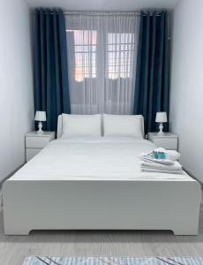 a bedroom with a large white bed with blue curtains at Inga Apartment in Turda