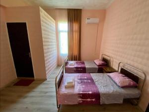 two beds in a room with a window and a door at Guest House Sveta in Martvili