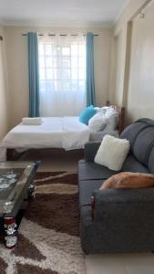 a living room with a bed and a couch at Woodgreek Studio Fully Furnished Apartment in Kisii
