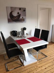 a white dining room table with black chairs and a red rug at Maya's Place in Leverkusen