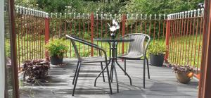 two chairs and a table on a patio with a fence at Henblas Holiday Cottages in Abergele