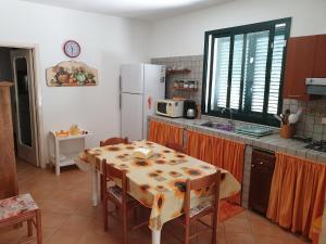 een keuken met een tafel en een witte koelkast bij Country house pool and sea in Agnone Bagni