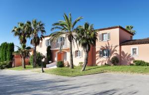una casa con palmeras frente a una calle en Appartement La Palmeraie Odalys Prestige Grimaud en Grimaud