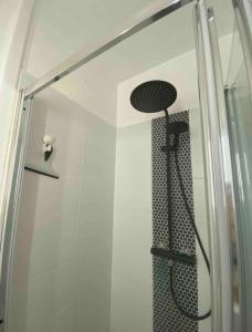 eine Dusche mit einer Glastür mit einem Duschkopf in der Unterkunft La petite Marcotte in Étretat