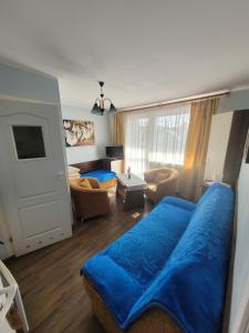 uma sala de estar com uma cama azul e um sofá em Dom gościnny Monika em Pobierowo