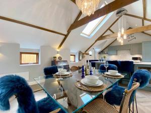 a dining room with a glass table and blue chairs at The Stables in Yate