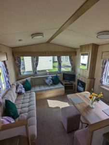 a living room with a couch and a table at The Jones's Family Caravan with private decking - Presthaven in Prestatyn