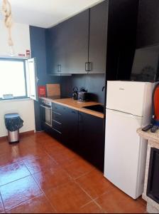 cocina con nevera blanca y armarios negros en Assossego House - Gerês, en Gerês