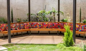 a wooden bench with a colorful couch in a garden at Hotel Las Camelias Inn by AHS in Antigua Guatemala