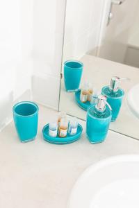 ein Badezimmer mit blauen Tassen, einem Waschbecken und einem Spiegel in der Unterkunft RELAX - GREEN mit Pool und Sauna in Scheidegg