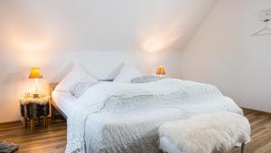 Un dormitorio con una cama blanca y una mesa con lámparas. en Dachwohnung mit Ofen und Freisitz, en Ühlingen-Birkendorf