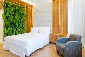 1 dormitorio con 1 cama blanca y 1 silla en Victory Business Hotel, en Juiz de Fora