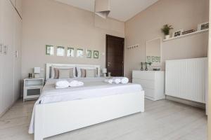 - une chambre blanche avec un grand lit blanc et des serviettes dans l'établissement Cozy seaside penthouse with sea & mountain view., à Vólos