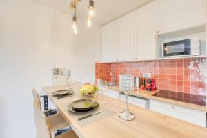 una cocina con una mesa de madera con copas de vino. en Super appartement avec vue sur la Tour Eiffel, en Le Kremlin-Bicêtre