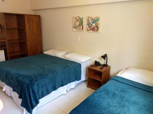 a hotel room with two beds and a night stand at Ilhamar Canas Hotel in Florianópolis