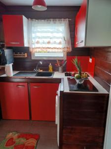 cocina con armarios rojos, fregadero y ventana en Couleurs îsles, en Montjoly