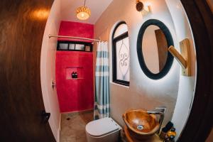 a bathroom with a toilet and a red wall at Niyana Oaxaca in Oaxaca City