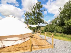 a wooden deck with a hammock and a tent at Heron's Retreat in Llandysul