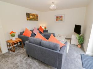 ein Wohnzimmer mit einem grauen Sofa und orangefarbenen Kissen in der Unterkunft 23 Moat House Close in Coventry