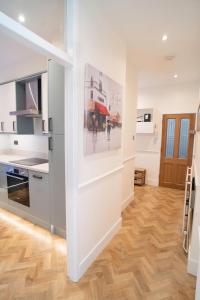 a kitchen with white walls and a wooden floor at Amazing Apt with 2 bathrooms close to Battersea Park in London