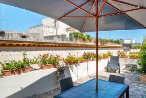 einen Tisch mit einem Regenschirm auf einem Dach mit Pflanzen in der Unterkunft Il Garbino Suite and Apartment in Lecce