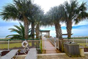 a white fence with palm trees and chairs on a beach at Beach Colony East 12C in Pensacola
