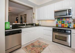 a kitchen with stainless steel appliances and white cabinets at Beach Colony East 12C in Pensacola