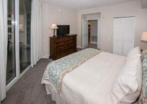 a bedroom with a white bed and a television at Beach Colony East 12C in Pensacola +40 photos