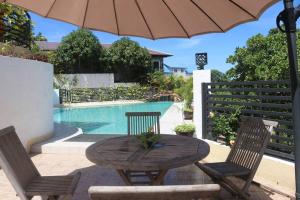 a table with two chairs and an umbrella next to a pool at Twin House Villa in Coron