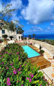 a swimming pool with flowers in front of a house at Al 33 Giri in Cefalù