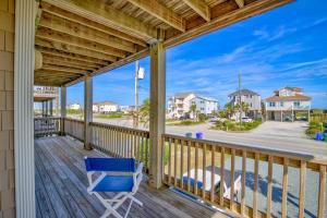 a deck with a blue chair and a view of a street at Surf and Sound in North Topsail Beach