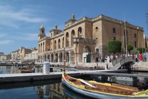 um edifício com barcos na água em frente a um edifício em The Olive 3 - Traditional Maltese Accommodation em Vittoriosa
