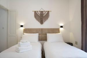 - 2 lits dans une chambre avec des draps blancs et des serviettes dans l'établissement The Olive 3 - Traditional Maltese Accommodation, à Il-Birgu