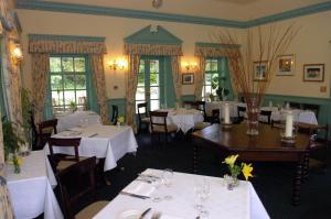 un restaurante con mesas y sillas con manteles blancos en Tyddyn Llan Restaurant with Rooms, en Corwen