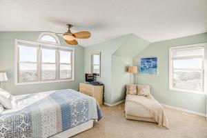 1 dormitorio con 1 cama, 1 silla y ventanas en Carolina Daze, en Topsail Beach