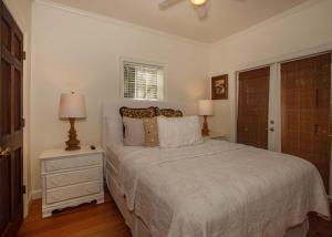 a white bedroom with a bed and two lamps at Porch Lane Cottage F in Fairhope