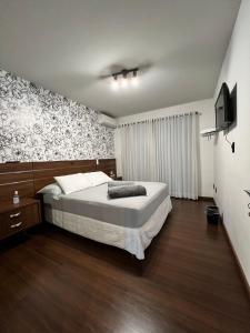 1 dormitorio con 1 cama y TV. en Pousada Central Jaraguá, en Jaraguá do Sul